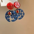 Vue macro de boucles d'oreilles ethniques avec fleur bleue évidée et perle de résine rouge - Tige d'oreille en argent sterling 925 Fleur creuse rouge bleu