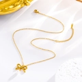 Detalle del collar dorado con colgante de lazo, perla y cierre de mosquetón ajustable - Collar