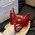 Elegant red patent leather underarm bag with a golden metal buckle and adjustable strap - Red