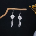 Macro detail of silver floral earrings with tassel hanging on a rustic branch - Butterfly Hollow Long Floral Dangle Style (E852-2)