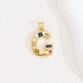 Detail of letter G pendant with colorful zircons and gold plating on textured backdrop - Letter G