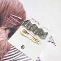 Detail von gewellter grauer Marmor-Haarklammer und goldener Metallklammer auf Karte - Wellenförmig Transparent Grau 2-Teiliges Set