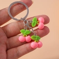 Detail view of pink resin cherry keychain with green leaves and metal chain - Cherry