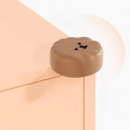 Brown circular silicone corner protector with smiley face on pink furniture edge - Poodle-Coffee