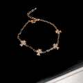 Dettaglio dei ciondoli a croce dorata con zirconi scintillanti su un bracciale a catena - Bracciale-Oro-Croce