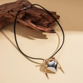 Detail shot of a silver heart pendant with a gold bow on a black velvet cord - Silver
