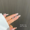 Detail shot of silver bow stud earrings held by hand showing 1x1.2cm size and 4.2g weight - Silver