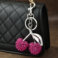 Pink rhinestone cherry keychain with silver metal clasp on a black quilted bag - Rhinestone Cherry Mixed Metal Leaf Rose Red