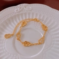 Gros plan détaillé du bracelet double gourde dorée avec motifs ajourés sur assiette blanche - Bracelet à Charms Gourde Creuse Or