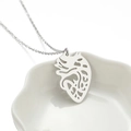 Collar con colgante de corazón anatómico plateado en un plato de cerámica blanca - Color Acero