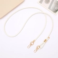 Detailed view of white PU leather crossbody bag strap with gold lobster clasps and buckles - White