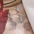 Close-up of silver leaf-shaped earrings with sparkling cubic zirconia on floral background - Silver Leaf Style