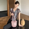 Pink woven bucket bag with drawstring liner shown in a minimalist lifestyle setting - Nude Pink (with inner bag)