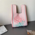 Pink knit tote bag with red rose pattern and green striped edges on a desk - Pink Rose