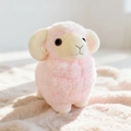 Peluche a forma di pecora rosa con corna a spirale su un morbido tappeto beige caldo - Rosa