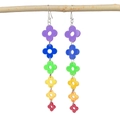 Detailed view of rainbow acrylic four-leaf clover tassel earrings on a natural branch - Rainbow Flower Hooks