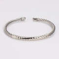 Detail of silver twisted cable bangle with diamond-cut pattern on polished stainless steel - Steel