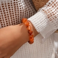 Close-up of translucent red acrylic bead bracelet with vintage geometric textures - Bracelet / Brown