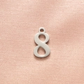 Close-up of polished silver number 8 pendant on a soft pink textured fabric background - Steel Color Number 8