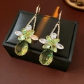 Vue macro de boucles d'oreilles dorées avec cristal goutte verte et détails en zircon - Crochet d'oreille - Vert