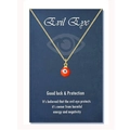 Detail of red evil eye charm on golden chain with dark blue symbolic gift card - 18K Gold Orange Bead (Black Eye)