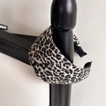 Detail shot of a wide leopard print headband hanging on a black bedpost with soft lighting - Grey Leopard Print