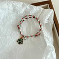 Detail of woven Christmas bracelet with green tree charm and silver bell on wood background - Christmas Tree