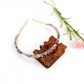 Detail view of handmade gold wire-wrapped purple crystal stone headband on a wooden stand - Gold + Double Row Amethyst