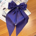 Large purple satin bow hair clip with long ribbons on a white display tray - Deep purple