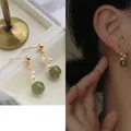 Elegant gold earrings with fresh water pearls and green beads shown on a model - 25# Golden Pearl With Green Jade-Style Bead Drop (Silver Needle)