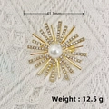 Golden sunburst brooch with central pearl and rhinestones on a beige textured background - KC Gold Snowflake