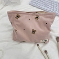 Vue détaillée d'une trousse en velours rose avec motif ours sur tissu blanc plissé - Rose