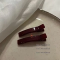 Dettaglio di due fermagli per capelli rosso scuro color gelatina su un piatto - Borgogna