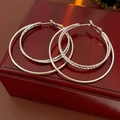 Detail of silver double-hoop earrings featuring smooth and textured bands on a wooden box - Silver with Silver Earring Post (Real Gold Plated)