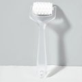 Close-up of a white toothed roller head on a translucent handheld massage tool - Clear