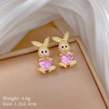 Close-up of golden bunny earrings with pink heart gemstone and small zircon inlay details - Pink Rabbit Stud Earrings (E434)