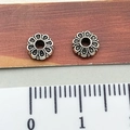 Set of two silver flower-shaped spacer beads on wood background with scale ruler - Hollow Flower Spacer Disc
