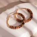 Macro-opname van gouden oorringen met luipaardprint pluche op witte stenen basis - Zilveren Naald Luipaard Pluche Cirkel Ring