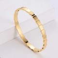 Bracciale placcato oro lucido con design geometrico a scaglie su supporto bianco - Oro