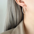 Pendientes de aro en C de acero plateado con textura de bambú usados por la modelo - Color Acero