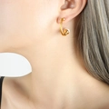 Eleganter gedrehter goldener Ohrring mit weißer Perle, von einem Model getragen - Ohrringe / Gold