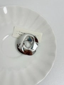 Detail of irregular silver circular brooch on a white textured ceramic dish - 6 Hollow Silver (Z-494)
