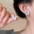 Detail of silver butterfly stud earring with shimmering white wings on model's ear - Silver Mother-of-Pearl Texture Butterfly Studs