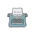 Vintage typewriter enamel pin in light blue with Be Nice slogan on white background - Blue Typewriter - Be Nice