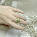 Elegant gold copper leaf ring with green enamel, worn by model on silk background - Adjustable Open / Green