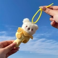 Cute white plush bear keychain in yellow outfit held against a clear blue sky background - Gourd Bear - Yellow