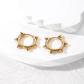 Golden punk spike hoop earrings for men in polished stainless steel on white pedestal - Gold