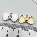 White enamel bow pendant with gold trim and rhinestone, shown with scale ruler - White Rhinestone Bowknot Tie