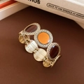 Dettaglio degli intarsi in smalto leopardato sul bracciale elastico placcato in oro - Oro-Ambra-Marrone
