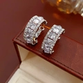 Macro detail of silver C-shaped earrings with sparkling cubic zirconia on a leather case - Pave Zircon C-Shape Stud Earrings with Silver Earring Post